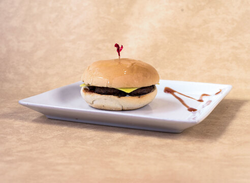 Classic cheeseburger served on white plate with grilled beef patty