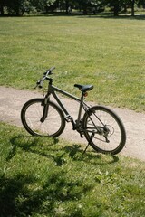 Fototapeta premium Grey mountain bike parked on grassy field and dirt path for outdoor family recreation and youthful fitness lifestyle concept