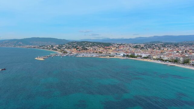 4K aerial view of Cannes Bay with Palais des Festivals, Vieux Port marina, Croisette beach and Le Suquet old town with Pre-Alps backdrop on the French Riviera.