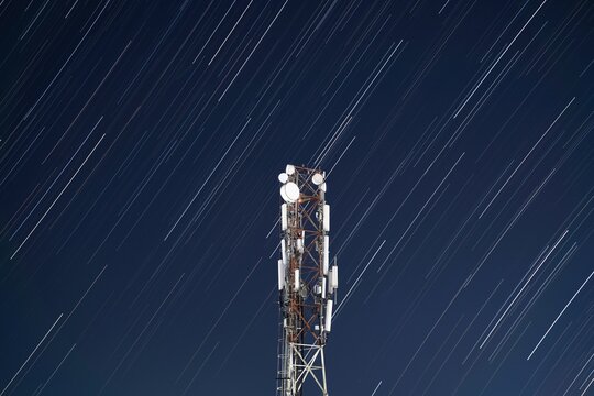 Telecommunication tower with star trails in a night sky landscape