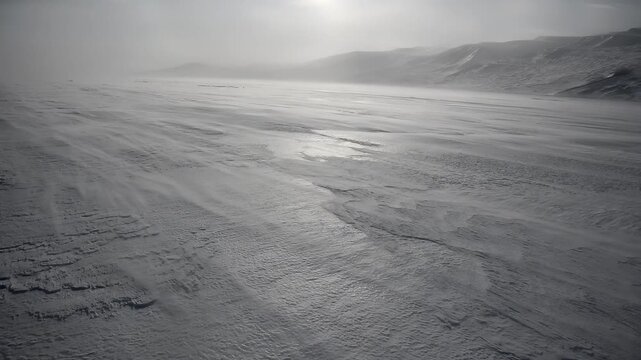 Expansive frozen landscape with wind sweeping across the snow-covered terrain