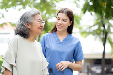 Obraz premium Asian female caregiver assistance senior patient with walker for physical rehabilitation and therapy, nurse supporting elderly woman walking in park, wellness and healthy retirement, medical concept.