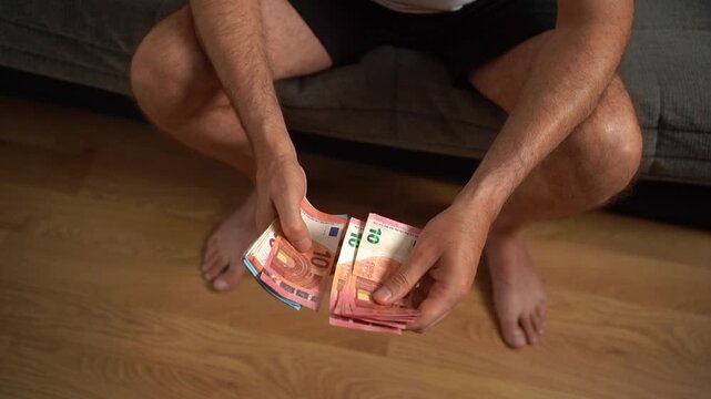Man's hands counting a stack of european union currency banknotes in his home bedroom