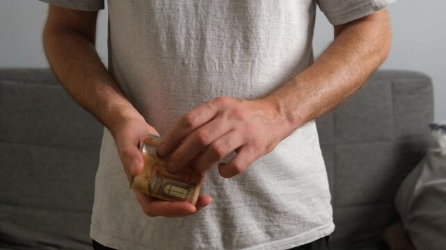 Close-up of a man's hands counting a stack of various euro banknotes indoors at home