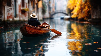 Obraz premium A serene gondola glides through a tranquil canal lined with autumn trees, capturing the essence of romance and adventure in a picturesque setting.