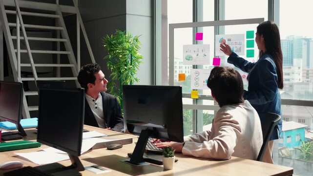 Businesswoman giving presentation on glass board, manager speaking to diverse team meeting in office, colleagues listening to financial report, coaching and employee leadership development program.