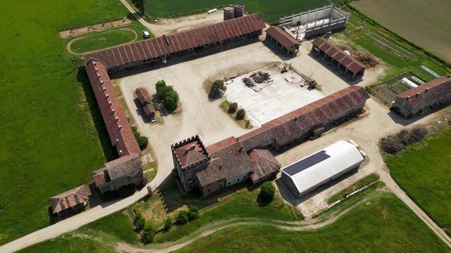 Aerial View of Agricultural Estate: An expansive rural estate, featuring traditional farm buildings with terracotta roofs and a modern solar-powered structure.