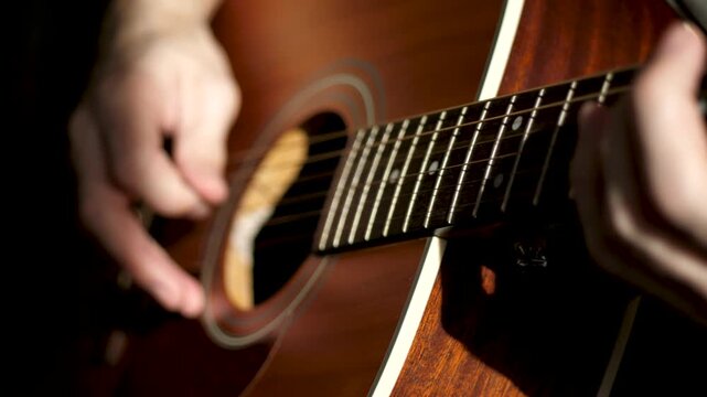 Close-up of musicians hands playing acoustic guitar, strumming strings during creative session. Music creation, artistic expression and authentic lifestyle, capturing emotion and sound production.