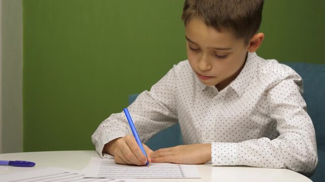 Child writing music homework at table, focused boy studying and practicing notes on paper. Concept of education, concentration and learning at home, cozy indoor atmosphere, horizontal video.