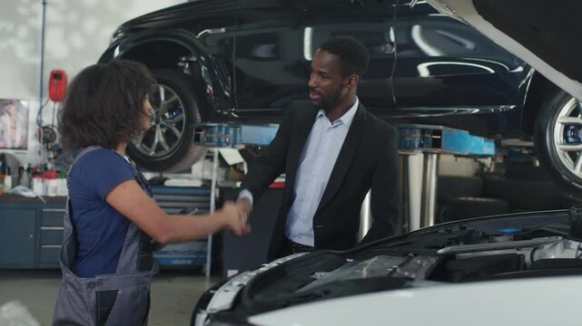 Woman mechanic explaining car problem to client, showing digital diagnostics on tablet. Inclusivity and professionalism in the auto industry.