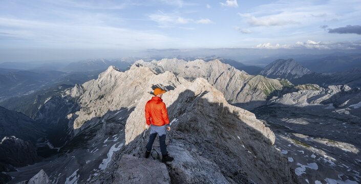 Mountaineer on a narrow rocky steep ridge, view of the H&ouml;llental and the Alpspitze from the Jubil&auml;umsgrat, in the evening light Zugspitze, Wetterstein range, Bavaria, Germany