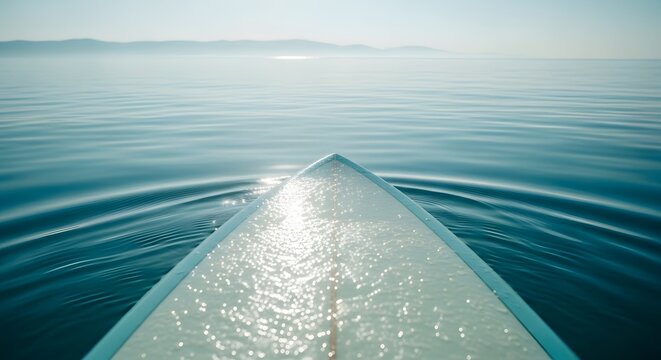 Point of view on surfboard in calm water. First person perspective and surfing meditation. Front tip of a surfboard gliding on still blue water under sunlight
