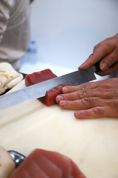 Chef experto en suchi cortando con un cuchillo japones de sushi at&uacute;n rojo crudo