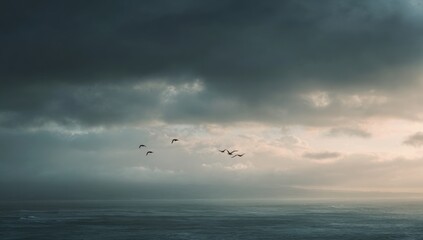 Fototapeta premium Flock of Birds Flying Over Calm Water Under Dramatic Stormy Sky.