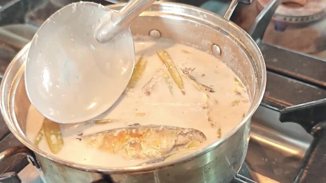 Cooking Thai coconut milk soup with mackerel and lotus stems.
