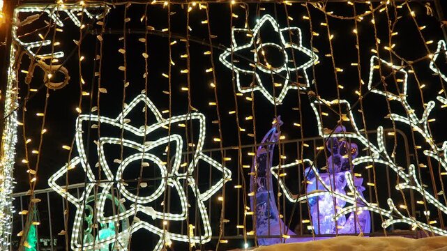 Christmas Garlands Light up the Night With Sparkling Designs in a Snowy Atmosphere. Bright lights and garlands decorate a snowy night background. Colorful patterns shine as Christmas celebrations fill