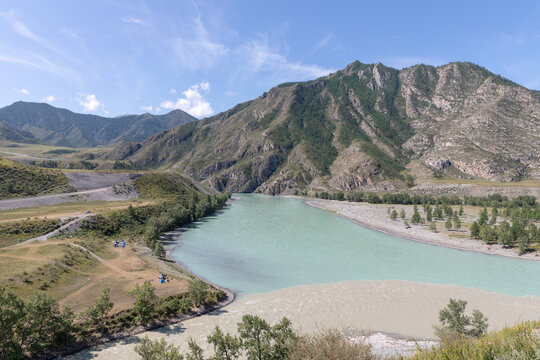 Wide view of the confluence of the Chuya and Katun rivers with contrasting turquoise and muddy water, surrounded by mountains and valley, Altai Republic, Russia