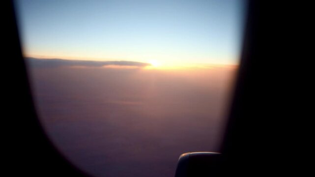 Plane At Sunset. Skyline Seen Through Airplane Window. Calm Evening In Flight With Glowing Clouds And Gentle Hues. Serene Journey As Sunset Illuminates Clouds Seen From Curved Airplane Window