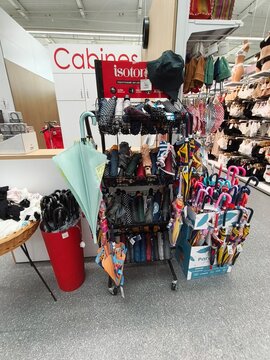Royan, France - May 10, 2026: E.Leclerc. Display rack featuring various umbrellas and rain gear in a retail store with a visible sign for 'Cabines' in the background