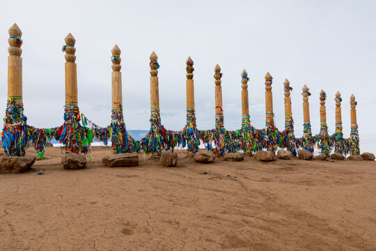 Traditional shamanic serge poles wrapped with colorful prayer ribbons on the sandy shore at Cape Burkhan, Olkhon Island, Lake Baikal, Russia