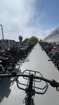 First person view riding a bicycle through a large outdoor parking facility in the netherlands on a sunny day