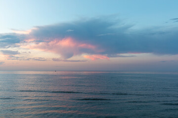 Fototapeta premium Serene seascape at sunset on the Caspian Sea near Derbent, Republic of Dagestan, Russia, with pastel pink clouds, calm water, and a wide open horizon