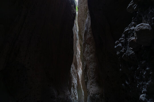 View inside the narrow Karadakh Gorge with towering rock walls and a thin strip of daylight above, a famous natural landmark in Dagestan, Russia, Caucasus region