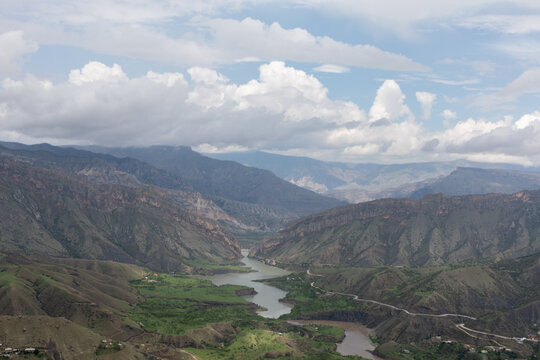 Wide panoramic view from Gunib fortress over a winding river in a deep mountain valley with dramatic clouds, Gunib, Republic of Dagestan, Russia