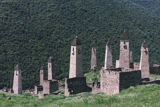 Ancient medieval stone watchtowers and ruins of the Erzi tower complex on a green mountain slope in Dzheyrakhsky District, Ingushetia, Russia