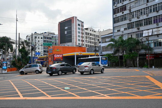 RIO DE JANEIRO, BRAZIL - MAIO 10: Cars and a public transit bus drive through a street intersection marked with yellow box junction lines past a Shell gas station and multi-story residential