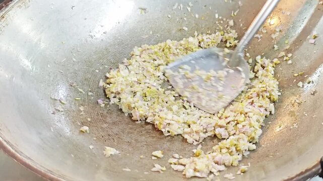 Step of browning chopped shallots in oil during cooking process.