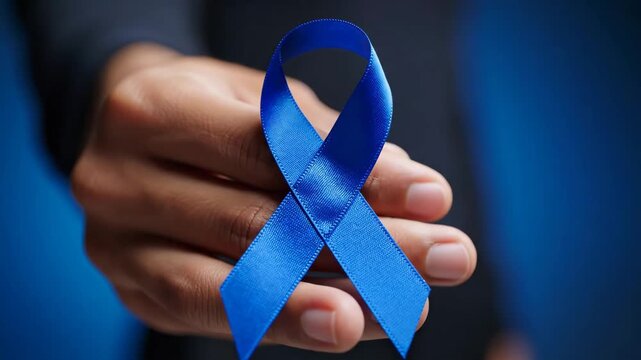 Blue Ribbon for Prostate Cancer Awareness - A close-up shows a hand holding a blue ribbon, which is a symbol for prostate cancer awareness and men's health.