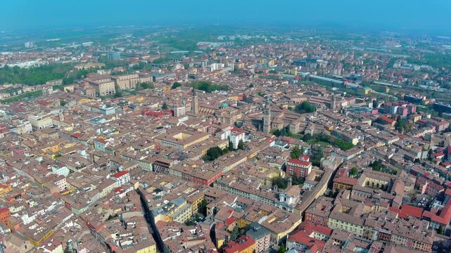 4K aerial view of Parma historic centre with Romanesque cathedral, octagonal baptistery, Palazzo della Pilotta and dense terracotta rooftops stretching across the Po Valley in Italy.