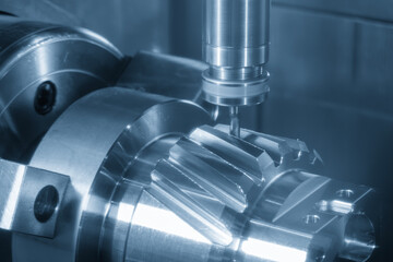 Fototapeta premium Advanced 5-axis CNC milling machine cutting a complex bevel gear shape on a transmission gear shaft.