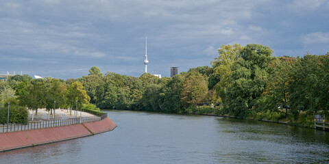  green borders of river Spree with Fernsehturm tower in the distance under a cloudy sky in the city of Berlin, Germany  © Kristof Lauwers
