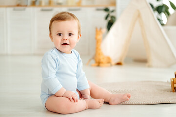 Fototapeta premium baby boy is smiling, little child is playing at home, early childhood development, baby is playing in the nursery at home