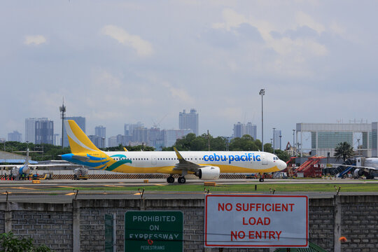 Manila, Metro Manila Philippines - 2025 July 13: A yellow and white commercial passenger jet taxiing on the runway