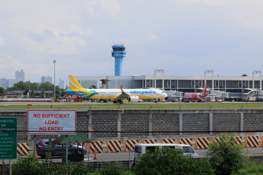 Manila, Metro Manila Philippines - 2025 July 13: A yellow and white commercial passenger jet taxiing on the runway