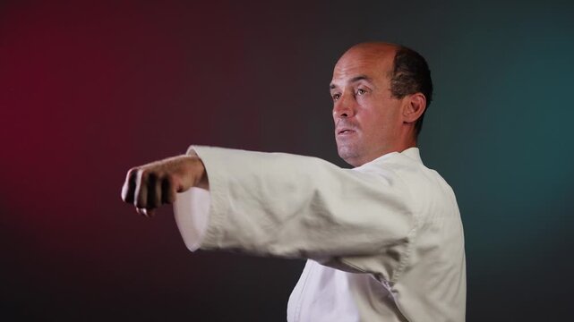 A young athlete blocks and punches against a multi-colored background with flashing red and green lights