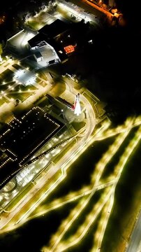Vertical video. Kaluga, Russia. Tsiolkovsky State Museum of the History of Cosmonautics, its illuminated parabolic dome and Vostok rocket monument, Drone footage at night over the Oka River embankmen