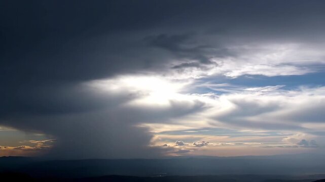 Dramatic Cloudscape Over Horizon - The video captures a dramatic sky where dark storm clouds encroach on a lighter, more serene section of the sky.