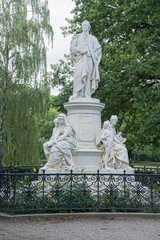Obraz premium Marble statue of writer and statesman Johann Wolfgang vo Goethe in Tiergarten park, Berlin, Germany. On the foot allegorical figures of Drama, Lyric Poetry (and Amor), and Science 