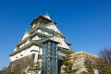 Osaka castle surrounded by trees and park in sunny day © leungchopan