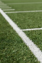 Obraz premium Closeup on green football field artificial turf with white yard line markings. Close view of sport ground surface texture for game or training. Nobody on empty pitch.
