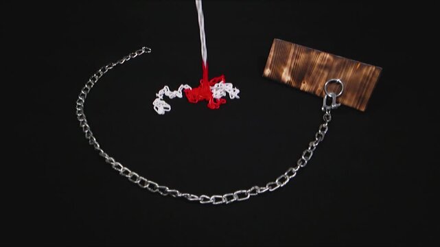 Slow-motion footage of metal chains falling from above onto a black background.