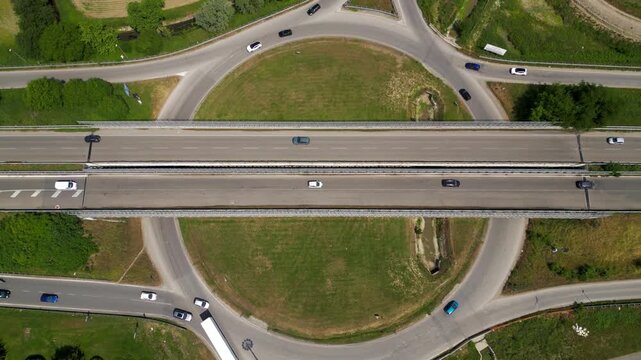 Highway Intersection Aerial View: Aerial shot capturing a complex highway intersection, with vehicles moving in multiple directions and a well-structured roundabout