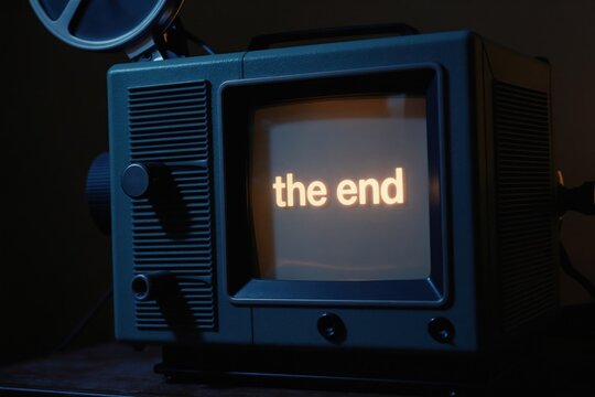 Old film projector shows text THE END on screen. Vintage movie machine displays final message. Retro cinema equipment used for film shows, nostalgia and entertainment.