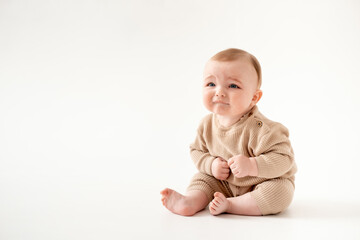 Fototapeta premium a crying baby on an isolated white background, a small boy crying or calling for his mother in a brown knitted suit