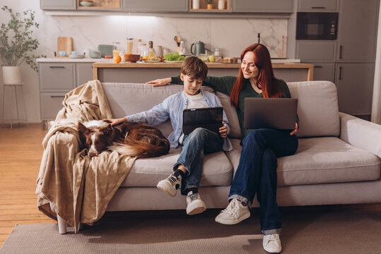 Full length shot of happy family and their dog relaxing with digital devices at home
