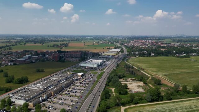 Urban Landscape: An expansive view showcases the vibrant intersection of a commercial area, a busy road, and the tranquility of rural farmlands, with scattered residential properties.